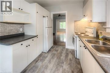 Kitchener apartment for rent - A kitchen with white cabinets and a brick backsplash.