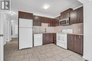 Barrie (Innis-Shore) townhouse for rent - A kitchen with white appliances and brown cabinets.