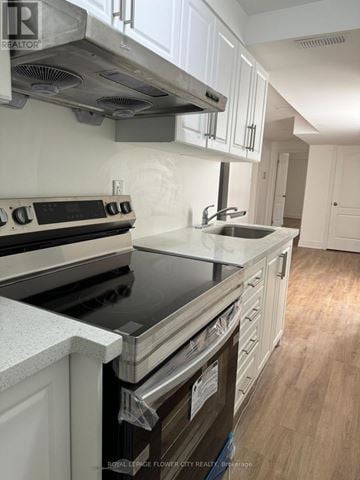Mississauga (Meadowvale Village) apartment for rent - A kitchen with white cabinets and a black stove top.