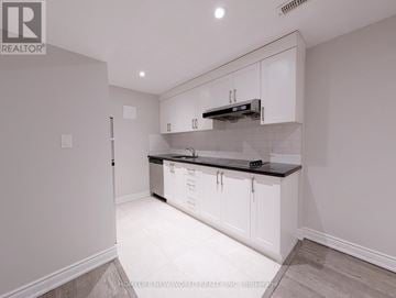 Toronto (The Beaches) apartment for rent - A kitchen with white cabinets and a black countertop.
