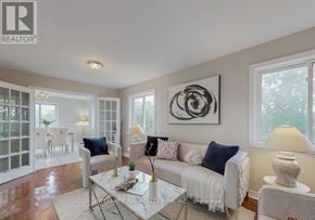 Brampton (Brampton West) apartment for rent - A living room with a white couch, a glass table, and a large abstract painting on the wall.