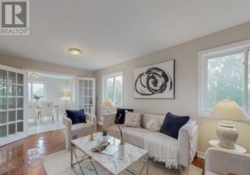 Brampton (Brampton West) apartment for rent - A living room with a white couch, a glass table, and a large abstract painting on the wall.