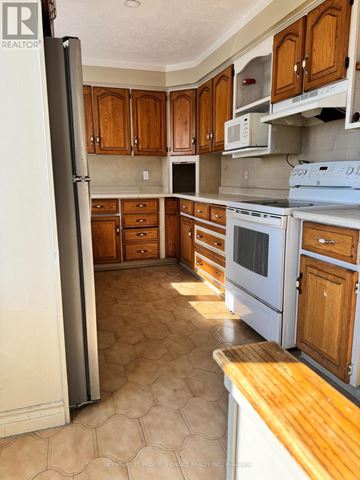 Mississauga (Malton) apartment for rent - A kitchen with wooden cabinets and a white refrigerator.