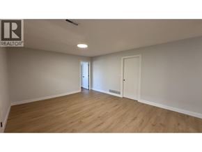 Burnaby apartment for rent - A spacious room with wooden flooring and white walls.