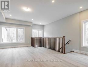 Innisfil (Lefroy) townhouse for rent - A spacious room with a staircase and large windows.