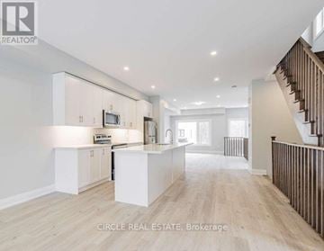 Innisfil (Lefroy) townhouse for rent - A spacious kitchen with white cabinets and a wooden staircase.