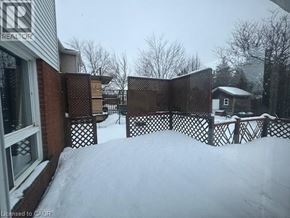 Waterloo apartment for rent - A snow-covered yard with a fence and a house in the background.