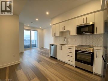 Kitchener condo for rent - A modern kitchen with white cabinets and stainless steel appliances.