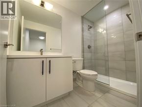 Kitchener condo for rent - A bathroom with a toilet, sink, and mirror.