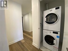 Kitchener condo for rent - A white washing machine is in a small room with wood flooring.