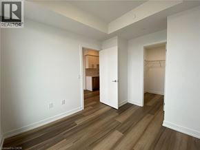 Kitchener condo for rent - A room with white walls and wood flooring with a doorway leading to another room.