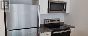 Hamilton (Waterdown) condo for rent - A stainless steel refrigerator is in a kitchen with a black counter top.