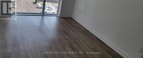 Hamilton (Waterdown) condo for rent - A room with a wooden floor and a large window overlooking a parking lot.