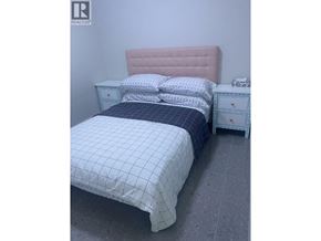 Vancouver apartment for rent - A bed with a pink headboard and a white bedspread with a blue patterned duvet.