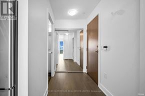Toronto (Mimico) condo for rent - A hallway with a door on the right and a window in the distance.