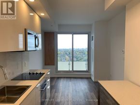 Toronto (Willowdale West) condo for rent - A modern kitchen with a view of the city through the sliding glass doors.