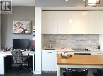 Toronto (Church-Yonge Corridor) condo for rent - A home office with a desk, chair, and a kitchen area with a sink and countertop.