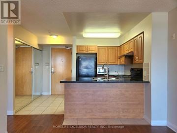 Markham (Milliken Mills East) condo for rent - A kitchen with wooden cabinets and a black refrigerator.