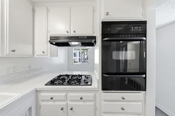 Corona Del Mar apartment for rent - A modern kitchen with white cabinets and a black stove top.