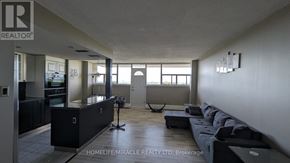 St. Catharines (Glendale/Glenridge) condo for rent - A spacious living room with a black sofa and a large window.