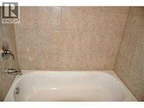 Calgary apartment for rent - A white bathtub with a shower head attached to the wall.