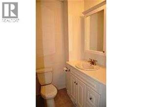 Calgary apartment for rent - A white bathroom with a toilet, sink and mirror.