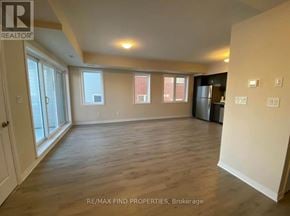 Kitchener townhouse for rent - A spacious room with wooden flooring and large windows.
