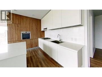 Burnaby apartment for rent - A modern kitchen with white countertops and wooden walls.