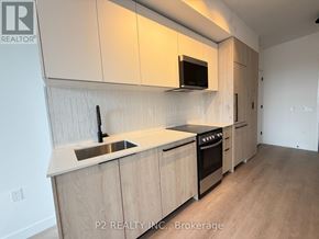 Toronto (Centennial Scarborough) condo for rent - A kitchen with wooden cabinets and a black microwave.