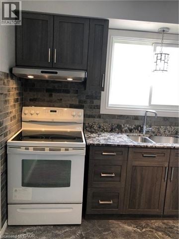 Brantford apartment for rent - A white oven and stove top are in a kitchen with dark wood cabinets.