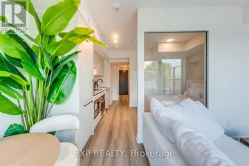 Toronto (Trinity-Bellwoods) condo for rent - A modern living room with a white couch and a dining table.