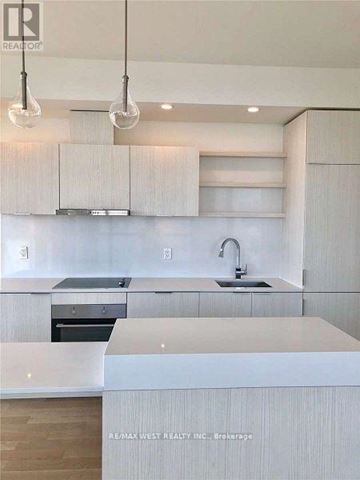 Toronto (Waterfront Communities) condo for rent - A modern kitchen with white cabinets and a center island.