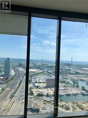 Toronto (Waterfront Communities) condo for rent - A view from a high-rise window looking out at a busy highway and a body of water.