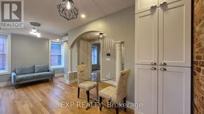 Ottawa multi-family for rent - A real estate listing photo of a living room with a grey couch, a glass table, and a brick wall.