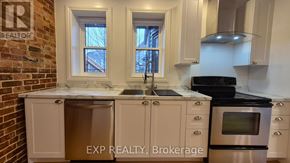 Ottawa multi-family for rent - A kitchen with white cabinets and a brick wall.