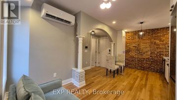 Ottawa multi-family for rent - A living room with a grey couch and a brick wall.