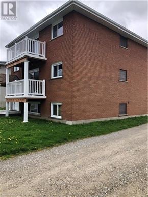 Brantford duplex for rent - A red brick building with a balcony and a gravel driveway in front.