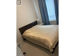 Richmond apartment for rent - A bed with a white sheet and a pillow is in the corner of a room with a window.