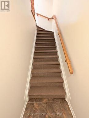 Ottawa condo for rent - A staircase with a wooden handrail and beige carpeted steps.