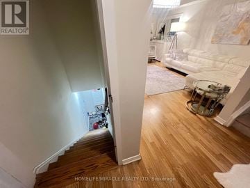 Oakville (Wm Westmount) townhouse for rent - A staircase leads to a living room with a white couch and a painting on the wall.