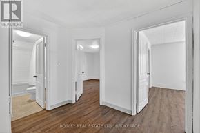 Niagara-On-The-Lake (Town) apartment for rent - A spacious room with wooden floors and white walls, with a doorway leading to another room.