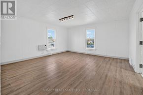 Niagara-On-The-Lake (Town) apartment for rent - A room with wooden flooring and two windows, one of which has a view of a cityscape.