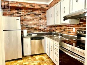 Toronto (Don Valley Village) townhouse for rent - A kitchen with a brick wall and stainless steel appliances.