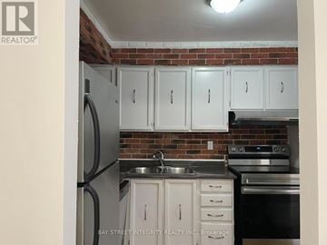 Toronto (Don Valley Village) townhouse for rent - A kitchen with white cabinets and a brick wall.