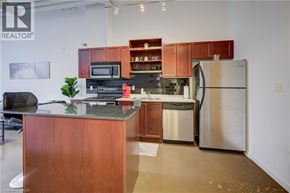 Kitchener condo for rent - A kitchen with a refrigerator, microwave, oven, and sink.