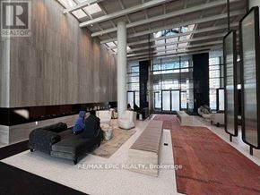 Vaughan (Vaughan Corporate Centre) condo for rent - A modern lobby with a person sitting on a couch.