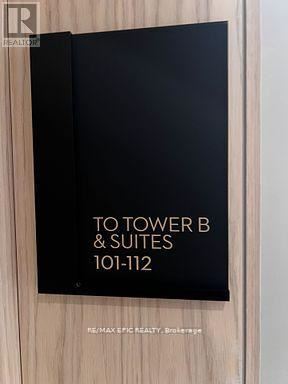 Vaughan (Vaughan Corporate Centre) condo for rent - A sign that reads "TO TOWER B & SUITES 101-112" is on a wooden door.