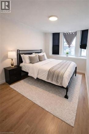 Hamilton apartment for rent - A bedroom with a bed, nightstand, and window.