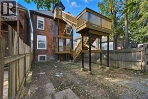 Hamilton apartment for rent - A backyard with a wooden deck and a staircase leading to a house.