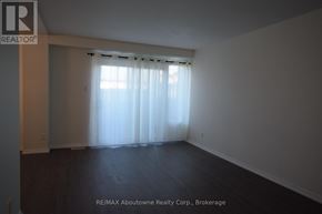 Brantford multi-family for rent - A large empty room with a window covered by sheer curtains.